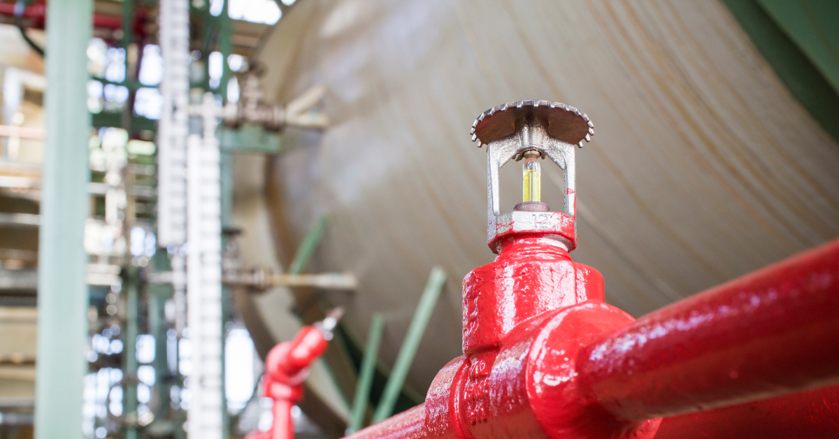 close up of a fire sprinkler with a red pipe in a factory